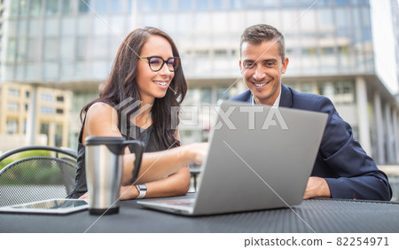 Two office, administration, finance or lawyers discuss work strategy looking into a laptop outdoors, smiling 82254971