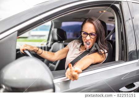 Raging female driver shows middle finger into a rear mirror during a rush hour traffic congestion Raging female driver shows middle finger into a rear mirror during a rush hour traffic congestion 82255151