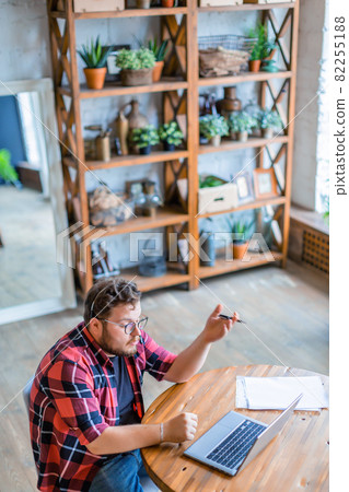Young hipster man working in front of laptop monitor at home. Online streaming or online video call. Vertical photo. 82255188