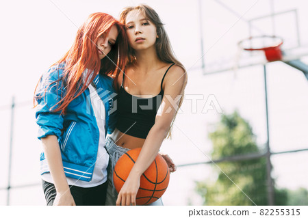 Portrait of two charming girls with a basketball on the sports field. Friendship, best friends, sports 82255315