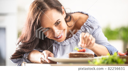 Woman does finishing touches of a cake decoration by putting mint leaf on top 82256631
