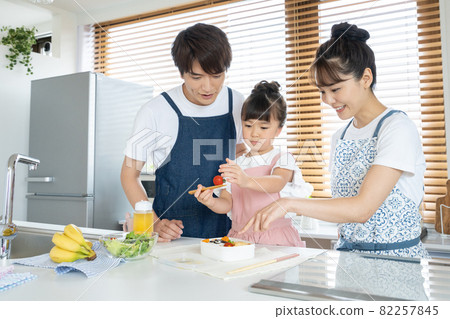 Elementary school girl, dad and mom making lunch in the kitchen 82257845