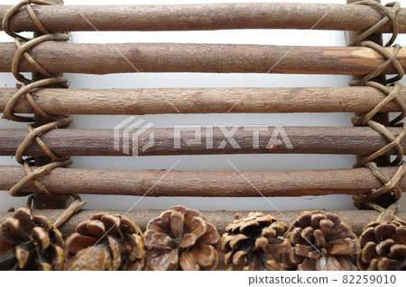 A pine cone on a plaque made of seven tree branches connected by vines A pine cone on a plaque made of seven tree branches connected by vines 82259010
