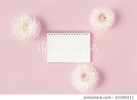Beautiful composition of opened blank spiral notepad framed with white flowers on trendy pink background in flat lay style for decoration design. Backdrop for your design. 82260311