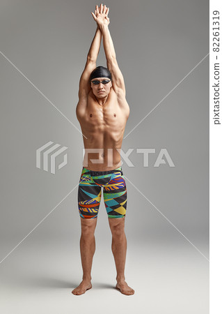 Portrait of a swimmer in mask, full-length portrait, young athlete swimmer wearing a cap and mask for swimming, copies of space, gray background 82261319