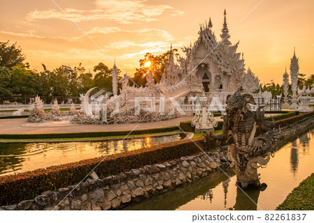 Beautiful view of White temple (Wat Rong Khun) in Chiang Rai province of Thailand at sunset. The Wat Rong Khun was designed by Chalermchai Kositpipat, a famous Thai visual artist. Beautiful view of White temple (Wat Rong Khun) in Chiang Rai province of Thailand at sunset. The Wat Rong Khun was designed by Chalermchai Kositpipat, a famous Thai visual artist. 82261837