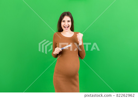 positive pregnancy test with two stripes against happy pregnant woman abdomen at Colored background. Future mother in gray dress. Pregnancy surprise. Copy space positive pregnancy test with two stripes against happy pregnant woman abdomen at Colored background. Future mother in gray dress. Pregnancy surprise. Copy space 82262962