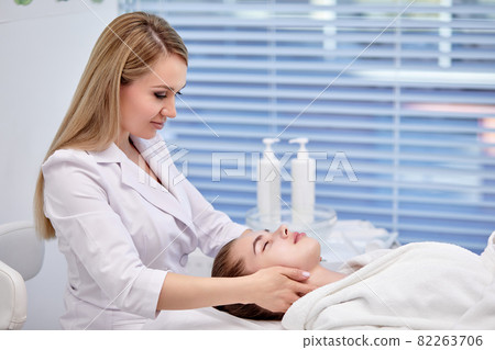 Young Woman enjoying anti aging facial massage. Pretty lady getting professional skin care Young Woman enjoying anti aging facial massage. Pretty lady getting professional skin care 82263706