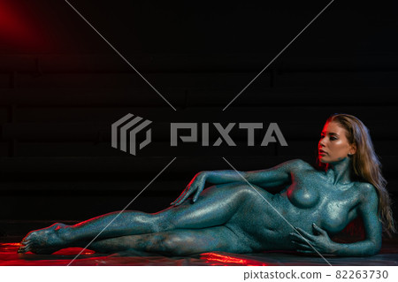 Gorgeous naked brunette posing painted in turquoise sequins. 82263730