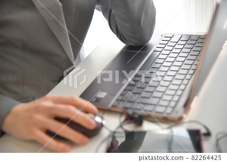 A person in a suit operating a computer with his elbows on the desk A person in a suit operating a computer with his elbows on the desk 82264425