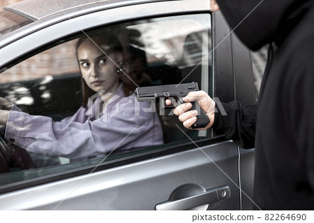 Bandit man robber holding handgun weapon gangster to hijack hostage woman driver car Bandit man robber holding handgun weapon gangster to hijack hostage woman driver car 82264690