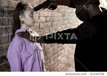 Afro american Thief armed man rob woman by gun on street, female is so scared, shocked face 82264706