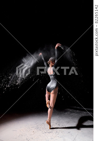 rear view on ballerina woman dancing and sprinkle flour on black studio background 82265142