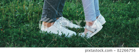 mother and daughter legs and shoes on the grass, only feet mother and daughter legs and shoes on the grass, only feet 82266756