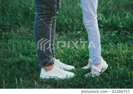 mother and daughter legs and shoes on the grass, only feet mother and daughter legs and shoes on the grass, only feet 82266757