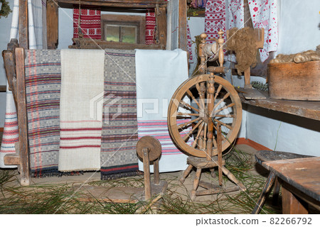 Vintage old spinning wheel. A device for making yarn against the background of an old interior and homespun cloths. Vintage old spinning wheel. A device for making yarn against the background of an old interior and homespun cloths. 82266792