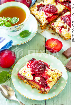 Sweet pie, tart with chocolate and fresh plum. Delicious cake with plum on kitchen table. Sweet pie, tart with chocolate and fresh plum. Delicious cake with plum on kitchen table. 82266917