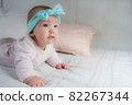 Newborn child wearing a diaper in white sunny bedroom. Newborn child relaxing in bed. Beautiful girl lies a happy smile, great design for any purposes. Happy family. Funny girl 82267344