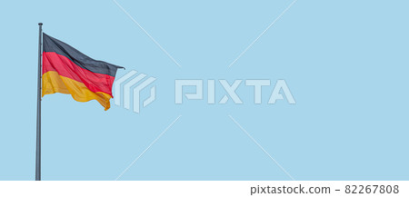Banner with a national black red yellow flag of Germany and at blue sky background with copy space, details, closeup. Concept of nationality, citizenship and patriotism. Banner with a national black red yellow flag of Germany and at blue sky background with copy space, details, closeup. Concept of nationality, citizenship and patriotism. 82267808