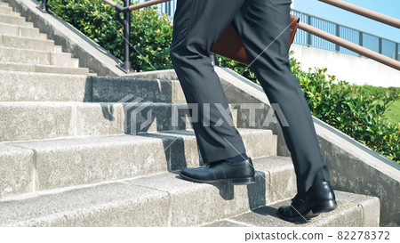 The feet of a businessman climbing the stairs 82278372