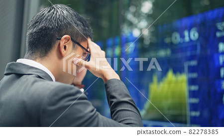 A depressed man in front of a stock board 82278385