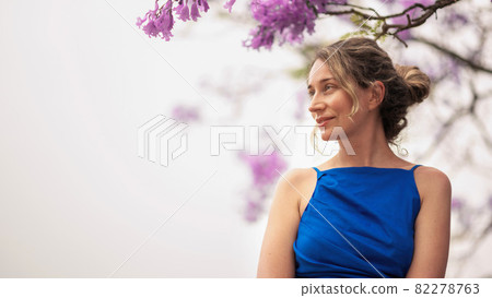 Caucasian woman in blue dress, pink tree flowers in Barcelona 82278763