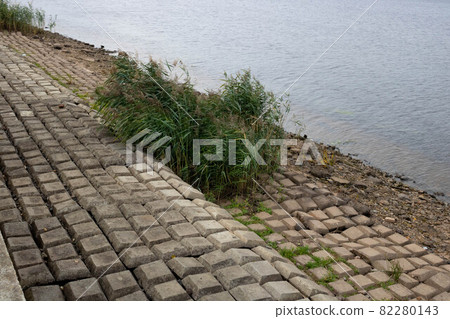 The river banks are reinforced with giant stones as a breakwater against erosion. Stone pavement on the embankment The river banks are reinforced with giant stones as a breakwater against erosion. Stone pavement on the embankment 82280143