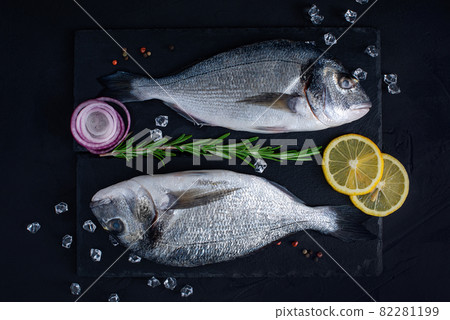 Raw Dorado lie on a black stone chopping Board. 82281199