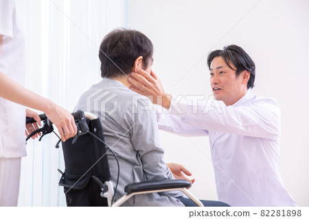 A doctor looking at the eyes and a patient in a wheelchair (ophthalmologist) 82281898