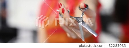 Woman hairdresser holding steel scissors in beauty salon closeup 82283083