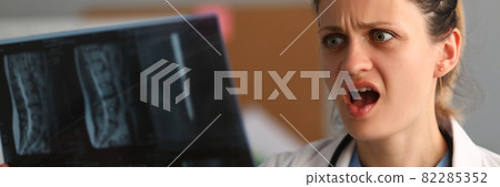 Woman neurologist holds x ray of sacral spine in her hand and is surprised 82285352