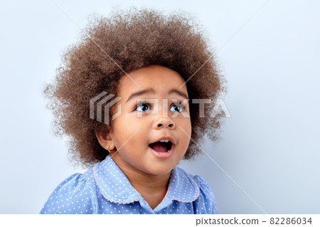 surprised african child girl in blue t-shirt looking up at something interesting 82286034