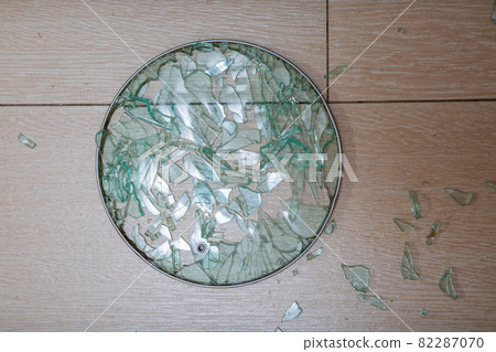 A close-up of a broken glass lid lies on a stake of tile. shards of glass shine. soft focus, top view 82287070