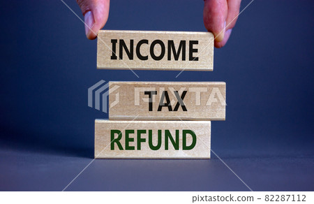 Income tax refund symbol. Wooden blocks form the words 'Income tax refund' on grey background. Male hand. Business and income tax refund concept. Copy space. 82287112