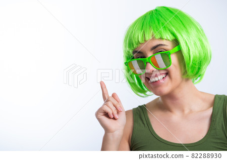 Cheerful young woman in green wig and funny glasses celebrating st patrick's day on a white background Cheerful young woman in green wig and funny glasses celebrating st patrick's day on a white background 82288930