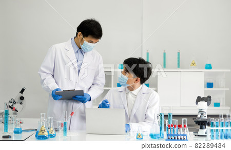 Two scientists with face mask discuss about blood samples of patients infected with Coronavirus disease 2019. Healthcare and medical concept. 82289484