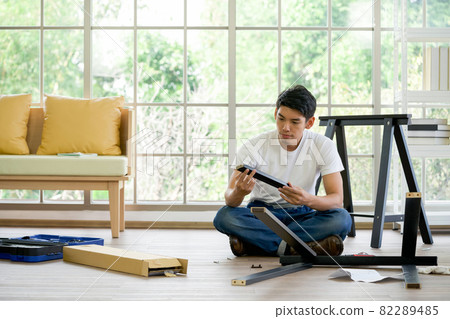 Handyman installing wooden bench in new house. House renovation service. Morning work atmosphere in the living room. 82289485