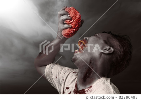 A scary zombie with blood and wound on his body eats the brain A scary zombie with blood and wound on his body eats the brain 82290495
