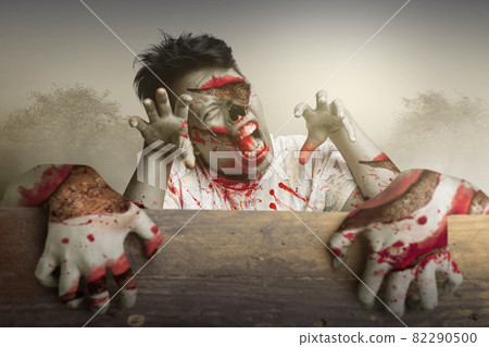 Scary zombies standing behind the wooden wall Scary zombies standing behind the wooden wall 82290500