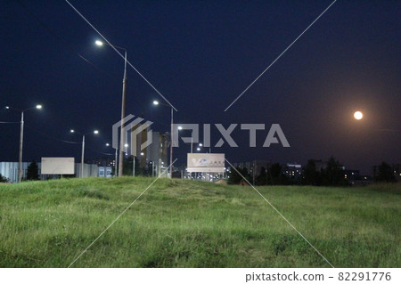 the moon on the outskirts of the city at night under the light of lanterns. night city landscape moon over grass the moon on the outskirts of the city at night under the light of lanterns. night city landscape moon over grass 82291776