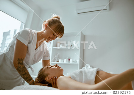 Adult female specialist is doing neck massage to a young natural beautyful female client 82292175