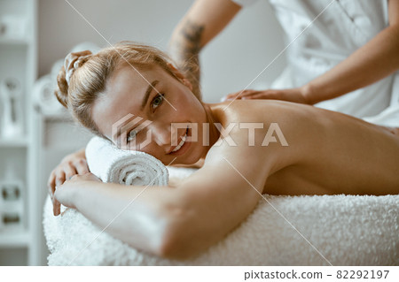 confident female specialist is doing relaxing body massage for beautyful slim caucasian lady at minimalistic spa salon 82292197