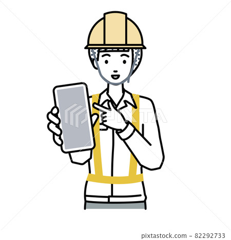 A woman at a construction site standing and pointing at her smartphone A woman at a construction site standing and pointing at her smartphone 82292733