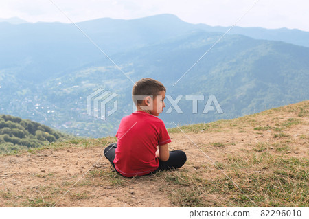 Little boy is sitting in nature. Hiking among hills and forests. Little boy is sitting in nature. Hiking among hills and forests. 82296010