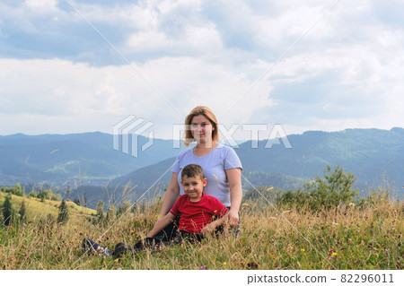 Family hiking in nature. Mother and son sit high among the hills and forest. Family hiking in nature. Mother and son sit high among the hills and forest. 82296011