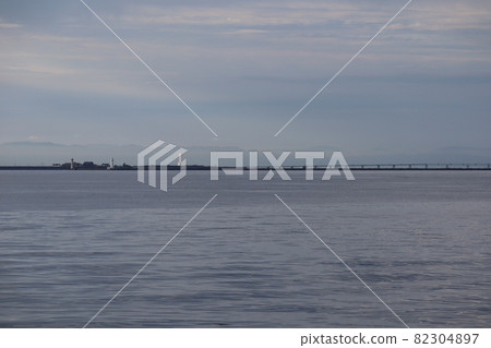 清晨多雲的天空，大海，碼頭，燈塔，橋樑，下面的陰霾山，和閃閃發光的摩天大樓 82304897