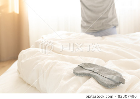 Sleeping mask on a bed with stretching woman in the background Sleeping mask on a bed with stretching woman in the background 82307496