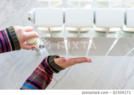Radiator adjustment closeup. Female hand adjusting radiator temperature 82309171