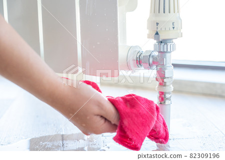 Female hand with rag cleaning water from heating radiator leak Female hand with rag cleaning water from heating radiator leak 82309196