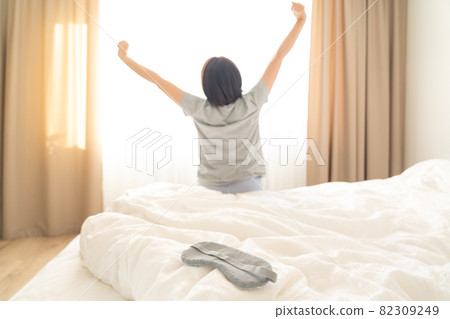 Sleeping mask on a bed with stretching woman in the background 82309249